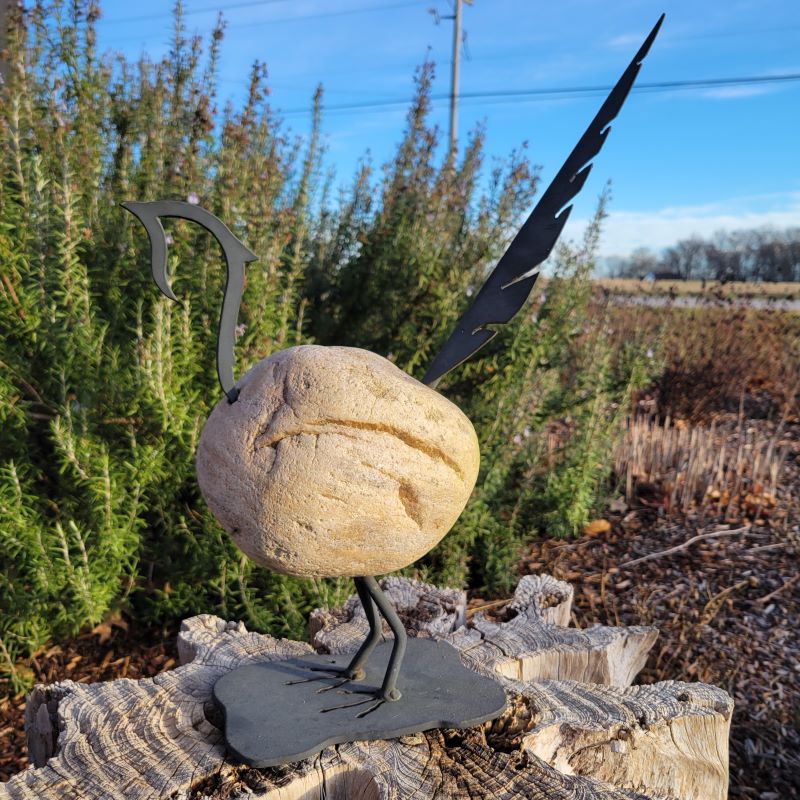 A black-painted iron and Minnesota fieldstone garden decoration in the shape of a pheasant.