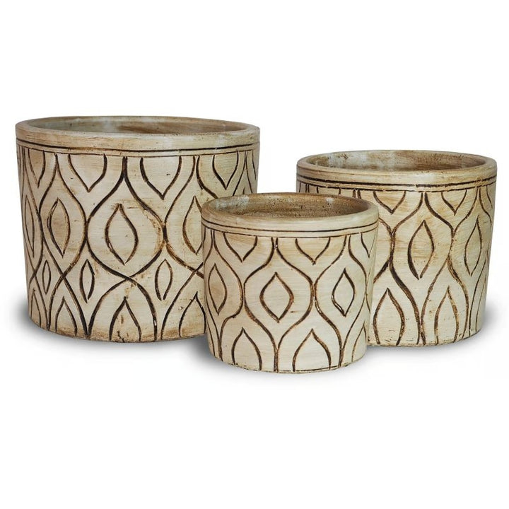 A stock photo of a trio of rounded planters with straight walls; planters are designed with a carved mid-mod design and are finished with matte cream white and black paint.