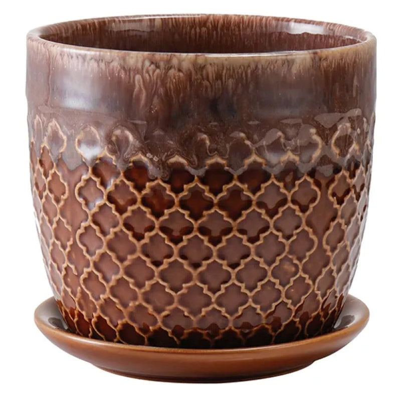 A stock photo of a rounded planter with built-in saucer; decorated with geometric abra-ogee pattern and finished in a compound brown and white drip glaze.