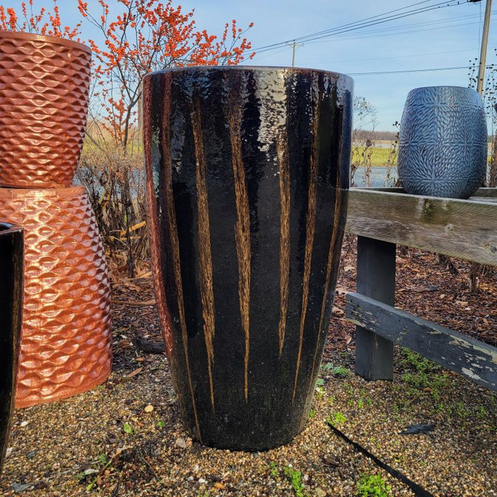 A narrow, rounded, vase-like planter with a chocolate stout (dark brown with cream-colored highlights) glaze 