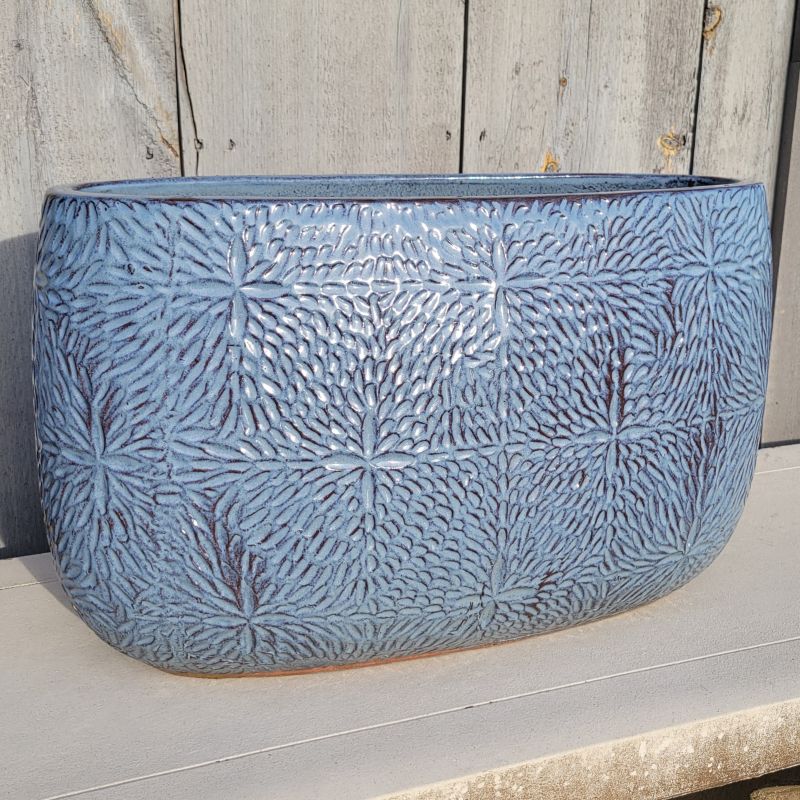 An oblong planter covered with a carved sand dollar pattern; finished in a blue-purple glaze over raw earthenware.