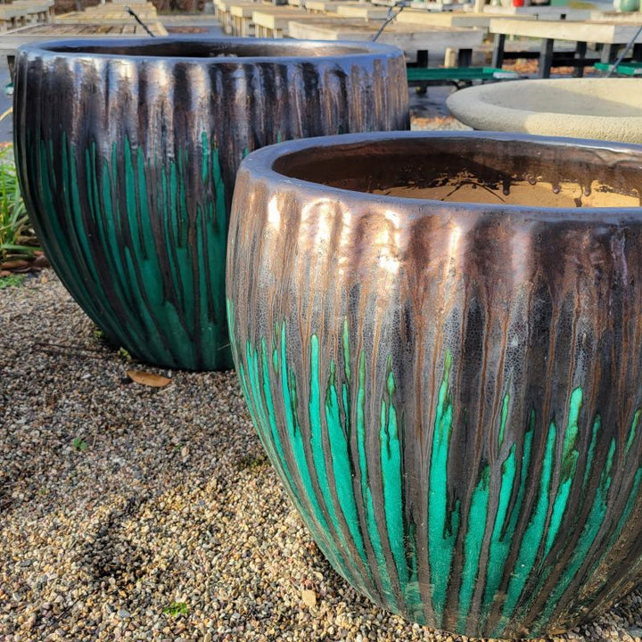 A pair of rounded planters with bowed sides and a sculpted fluting design around their perimeters; finished with a metallic jade-grade and black-bronze drip glaze.