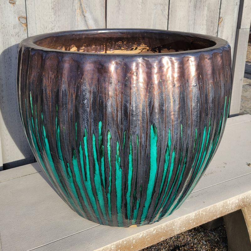 A rounded planter with bowed sides and a sculpted fluting design around its perimeter; finished with a metallic jade-grade and black-bronze drip glaze.