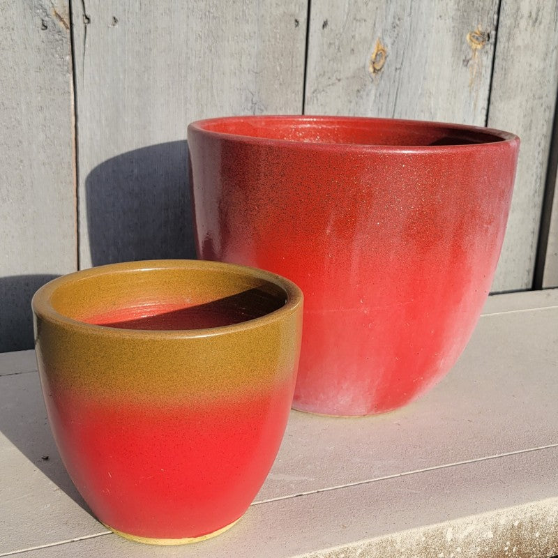 A pair of rounded, egg-cup shaped Athens planters with different degrees of bright red to gold ombre; one pot is smaller and one pot is larger.