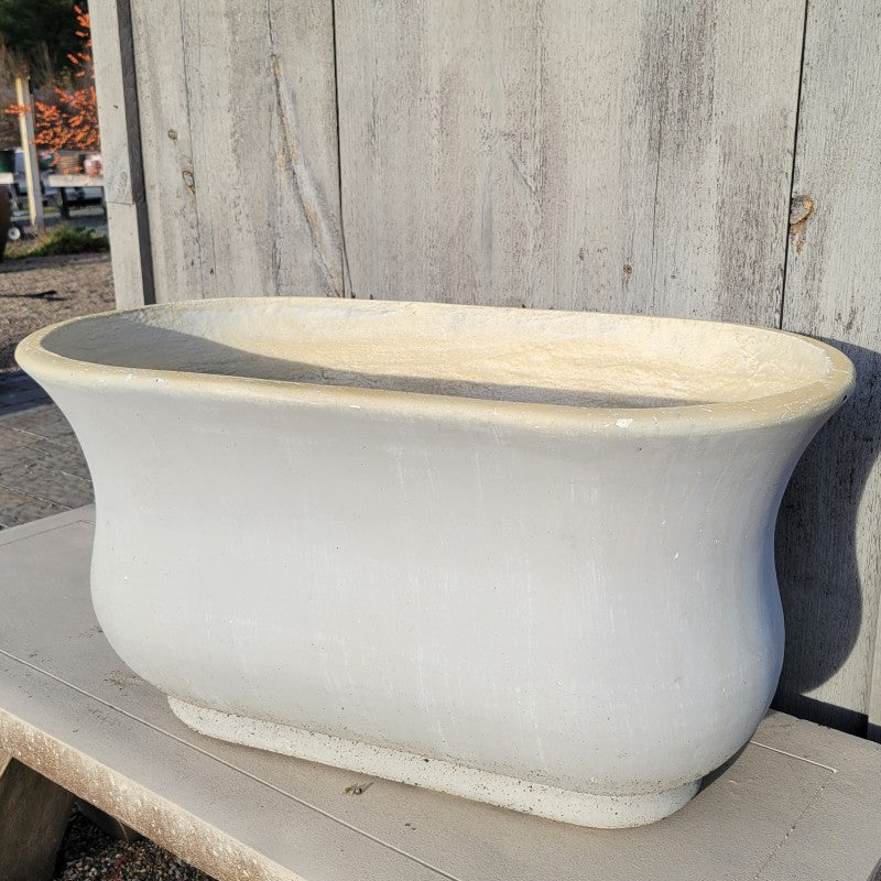 A large, bathtub shaped fiberglass planter with a matte stone-gray finish.