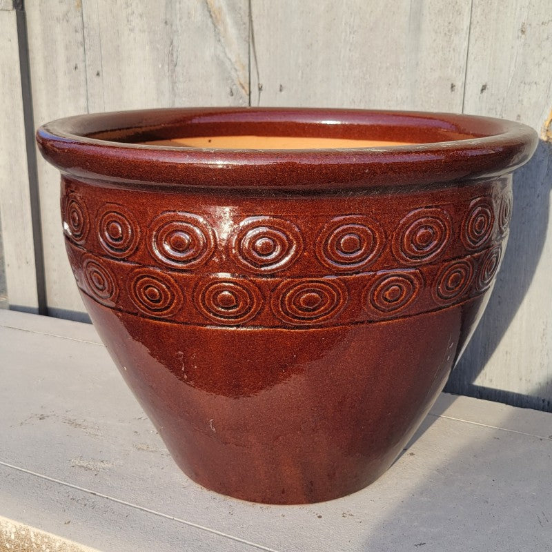 A rounded pot with a decorative band of bull's-eye designs under the rim; finished with a dark chocolate-brown glaze.