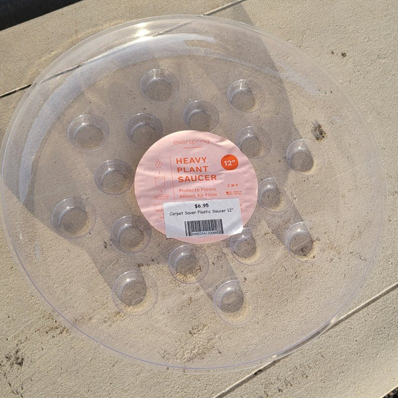 A rounded plastic saucer for placing under plant pots, featuring a pink tag and several divots to better catch draining water from pots.