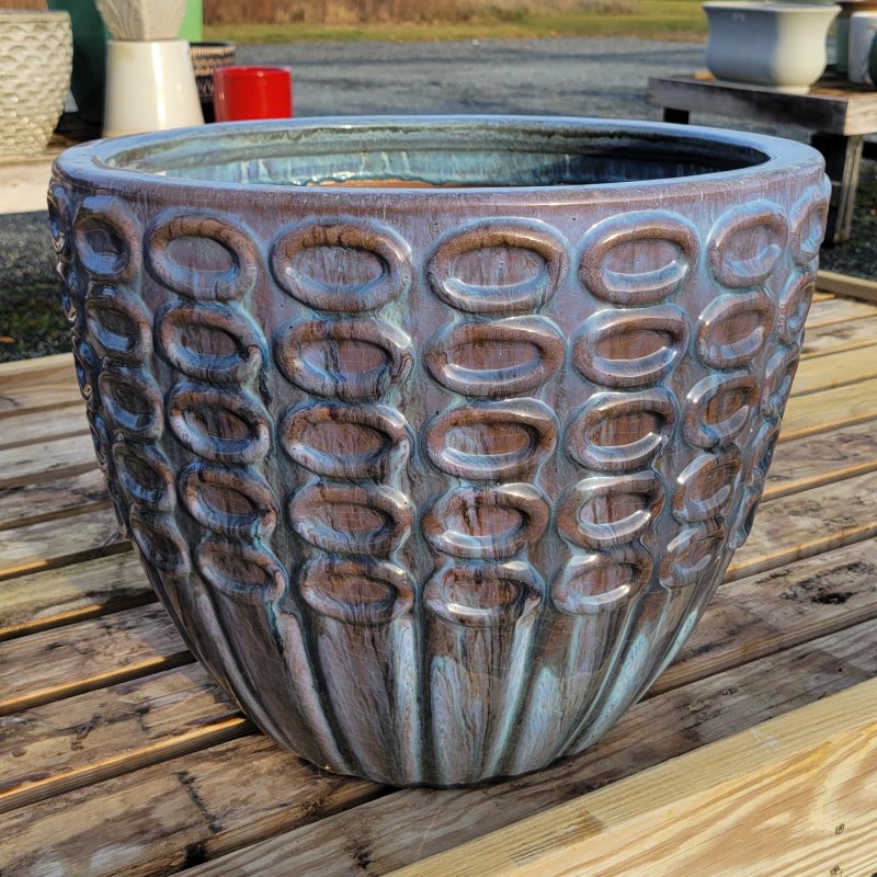 A rounded planter with sculpted ring and bar design; finished with pearlescent purple and black drip glaze.