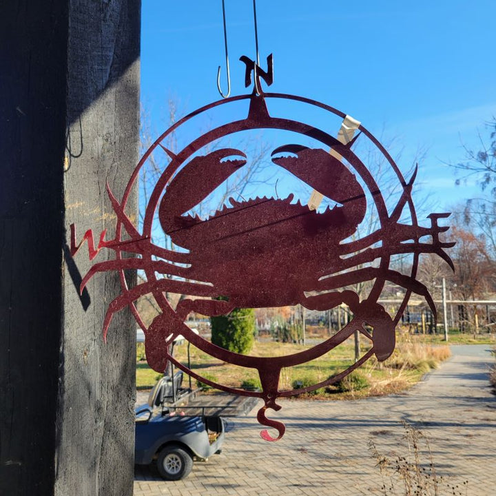 A hanging Compass Crab Metal decoration, with crab and compass rose elements, finished with a metallic red powder coating.