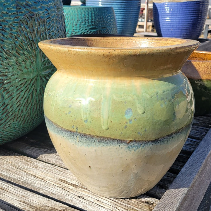 A rounded kettle-type pot with bowed walls and a pronounced, flared lip; finished with a cream-white to wasabi green to earth-tone brown ombre glaze.