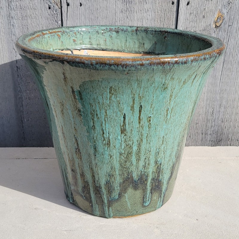 A plain, flared, rounded planter finished in a dark and lighter green drip glaze.