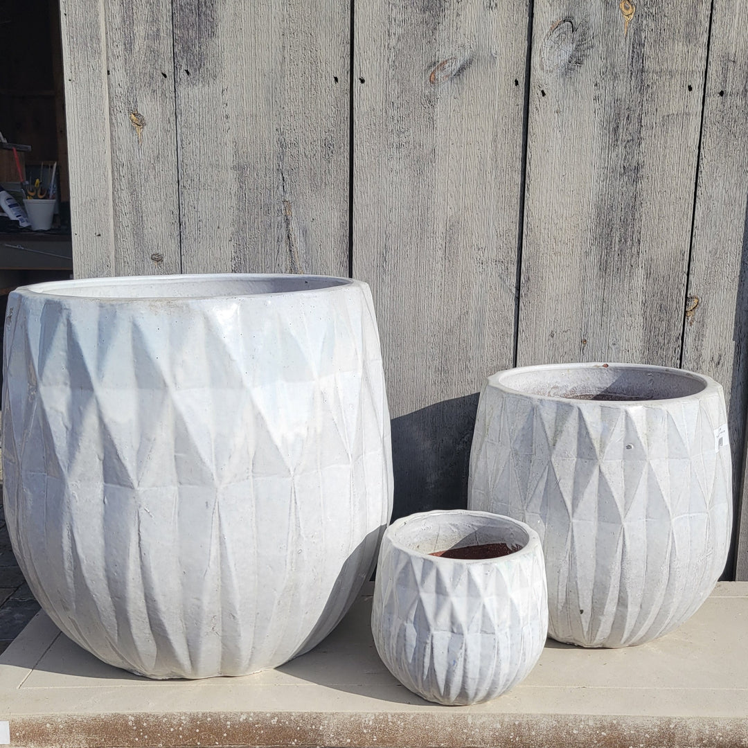 A trio of squat, rounded planter with sculpted diamond design elements and white glaze; placed next to each other for size comparison.