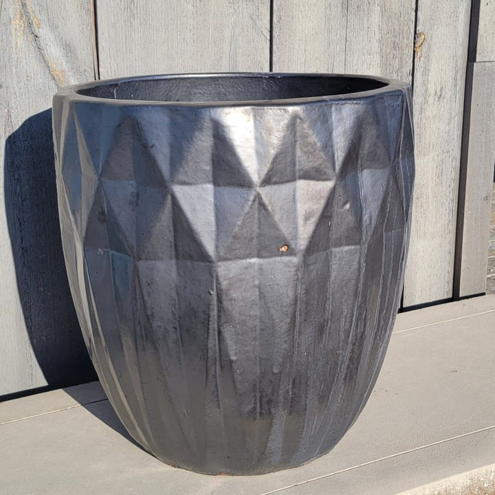 An upright, narrow, rounded planter with sculpted diamond-shaped texture; finished with a metallic silvery graphite glaze.