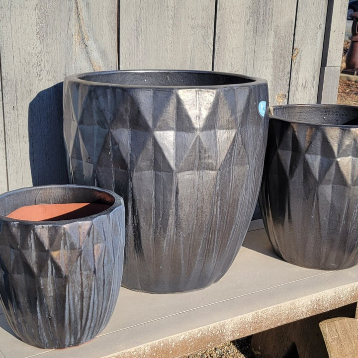 A trio of narrow rounded planters with sculpted diamond-shaped texture and finished with a silvery glaze. The planters are placed near each other for size comparison.
