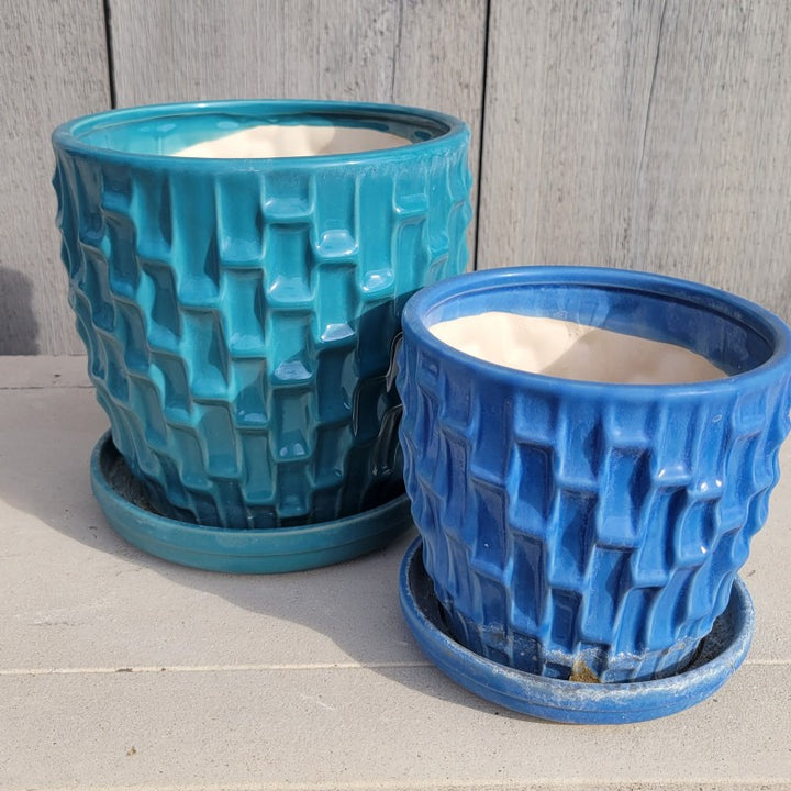 A pair of Escher Planters, both decorated with single-like geometric designs; the larger of the pair is teal blue and the smaller is a light cobalt blue.