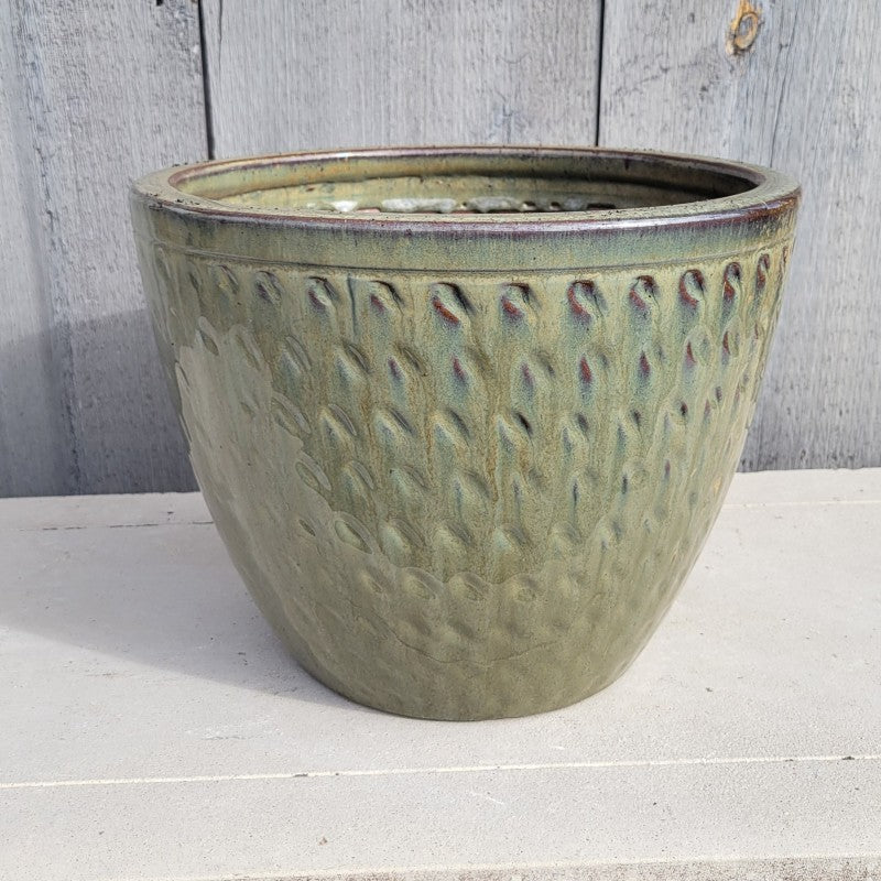 A rounded planter with a carved divot design at regular intervals; finished with an olive-green heathered glaze.