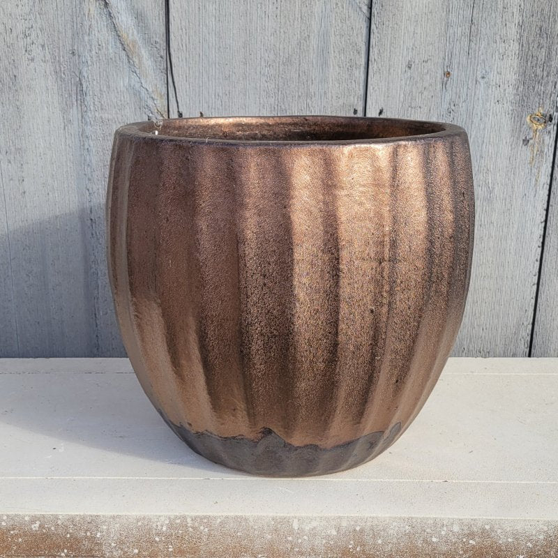 A rounded planter with bowed walls and a fluted appearance; finished in a metallic bronze glaze.