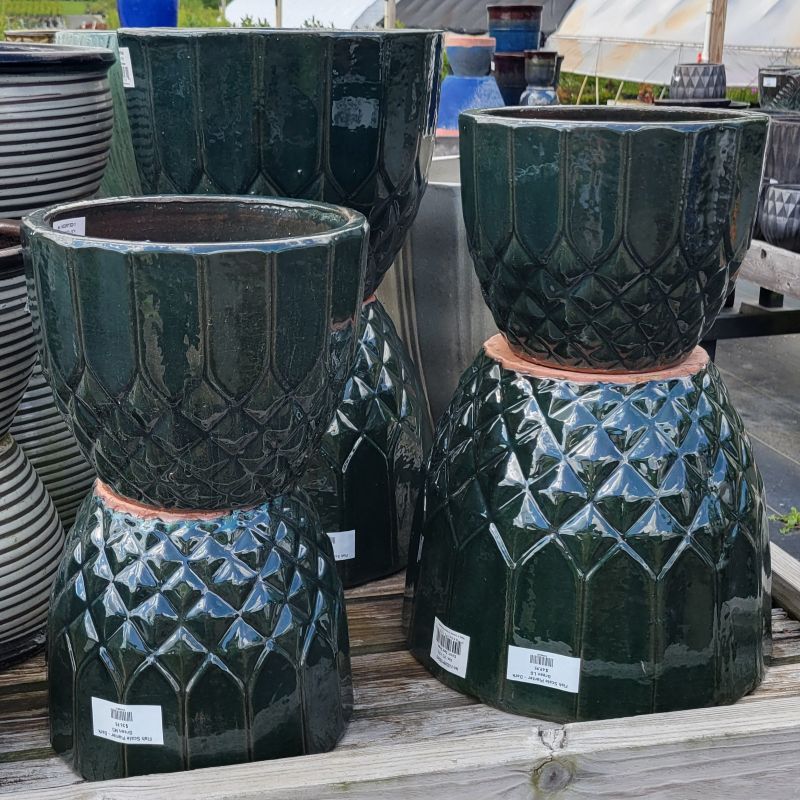 A collection of glossy, dark green glazed Fish Scale pots with geometric shingled appearance