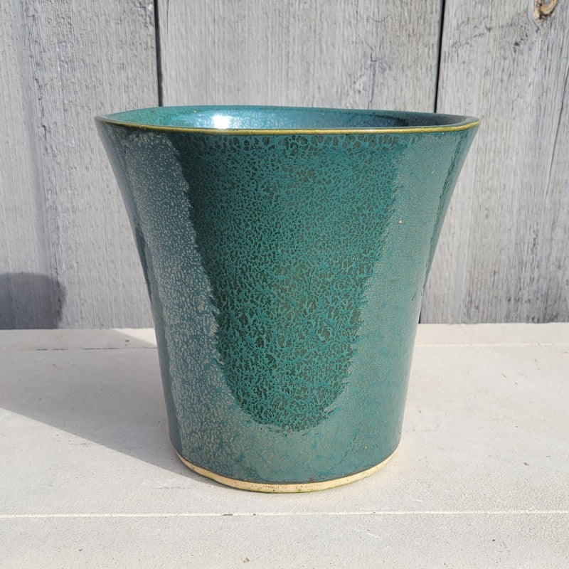 A small, flared, rounded planter with a metallic green speckled glaze.