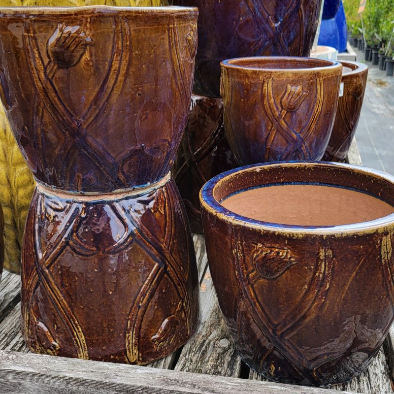 A photo of several brown and blue/yellow accented Flourish planters with a stylized tulip design