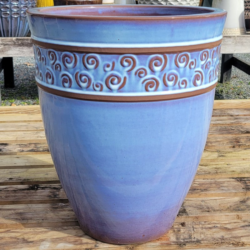 A tall, rounded planter with pearlescent pale-purple glaze over earthenware; decorated with a band near the lip with sculpted swirl designs.