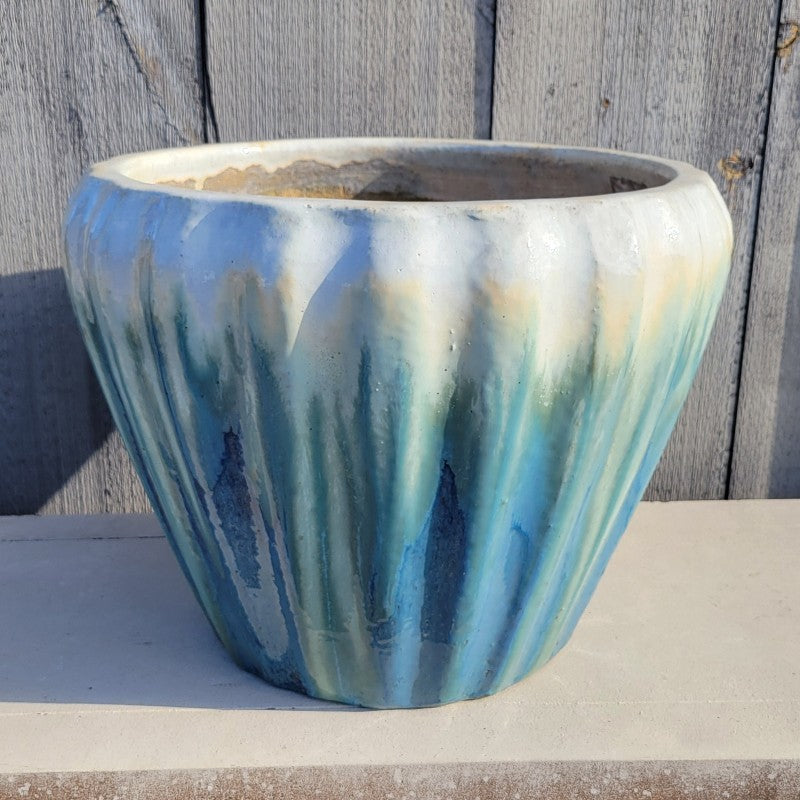 A flared, rounded Honorable planter with bowed walls and a fluted exterior; finished with a dark sea-blue to cream-white ombre glaze.