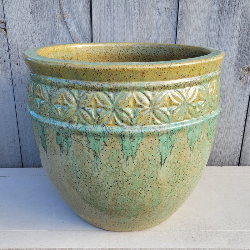 A rounded Kousa planter with a decorative band of geometric shapes resembling four-petaled flowers; finished in a marbled glaze of ochre, avocado green, and jade green.