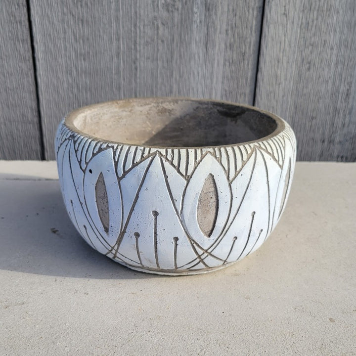 A rounded, bowl-style Lagos Bowl planter with a removable drain plug and a carved, abstract design on the exterior. Finished in matte white glaze and raw earthenware.