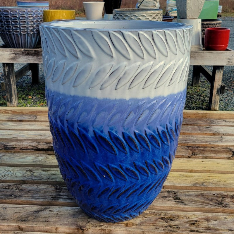 A narrow, rounded Lake Storm planter with sculpted laurel pattern and an ombre glaze that fades from dark blue at the base to white at the upper lip.