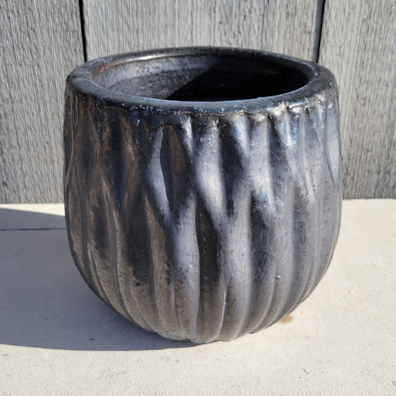 A squat, rounded Lambrate planter with a sculpted diamond/geometric design and a smooth, round lip; finished with a metallic graphite gray glaze over chunky, natural earthenware.