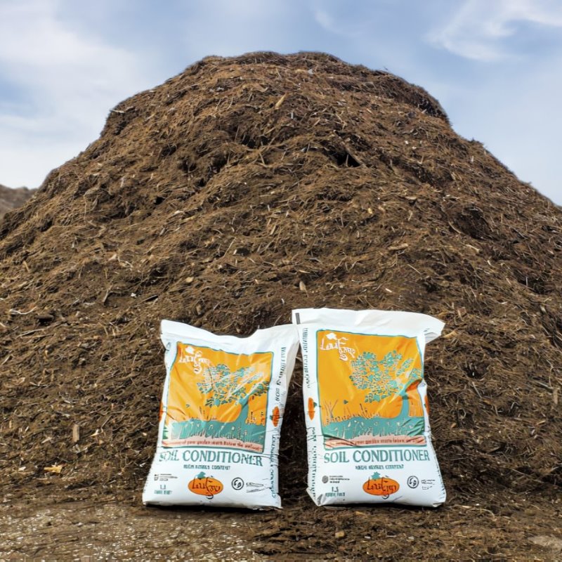 LeafGro Soil Conditioner bags in front of a large pile of compost.