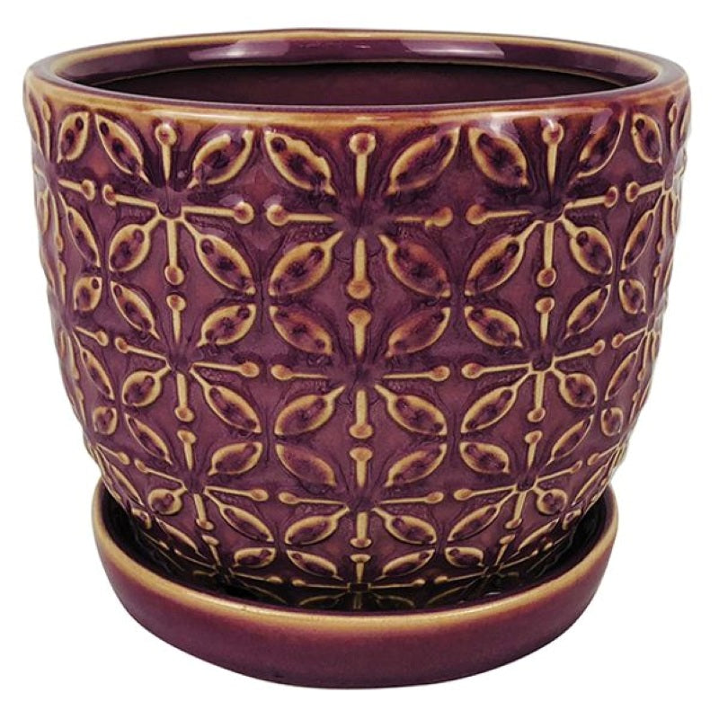 A stock photo of a rounded planter with built in saucer and sculpted floral/leaf-scroll design; finished in a glossy lilac purple glaze.