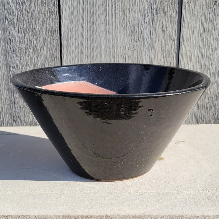 A low, flared, round basin-style planter; finished with glossy black glaze over earthenware interior.