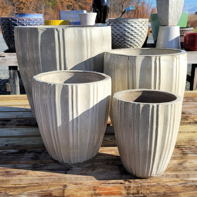 A set of four Lucien planters with fluted decoration and heathered cream-white glaze; set includes small, medium, large, and extra large planters.