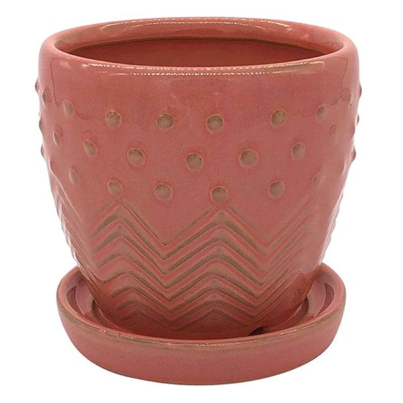 A stock photo of a rounded planter with built-in saucer and a multi-piece design with carved groove and sculpted dot elements; finished in a coral pink glaze.