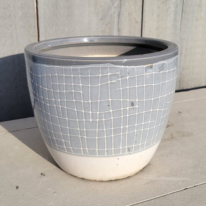 A rounded planter with carved cross-hatch pattern; finished with pale gray and cream-white glazes over different parts of the design with a darker gray lip.