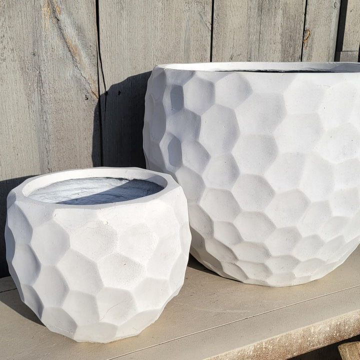 A pair of rounded fiberglass Moondance planters with a faceted, gem-stone like appearance; both small and large planter are finished in a matte, bone-white glaze.