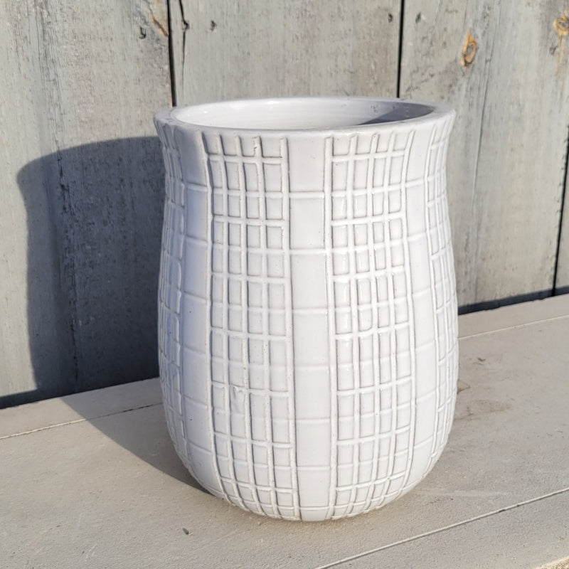 An upright, round, urn style planter with carved geometric line design; finished in a gloss white glaze.