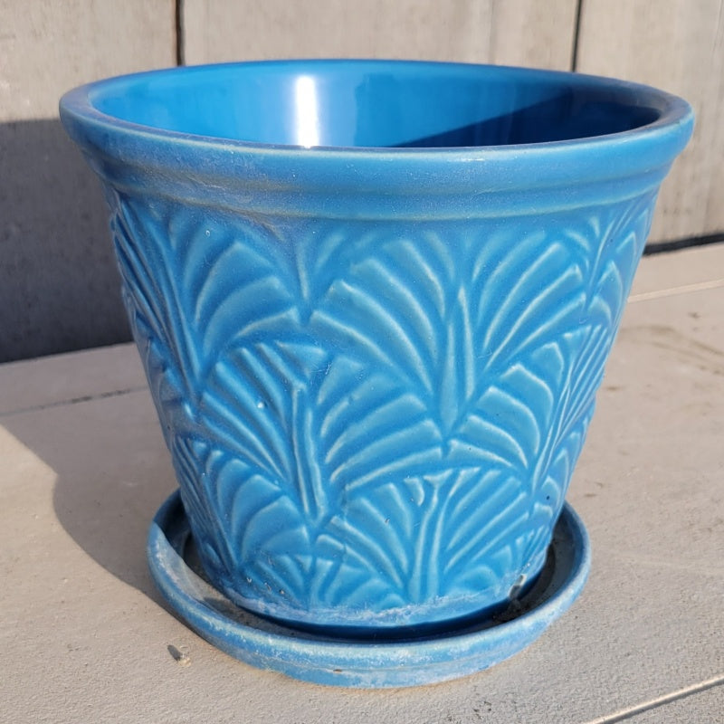 A vase-like Nouveau planter covered in palm frond designs and finished in a turquoise blue glaze.