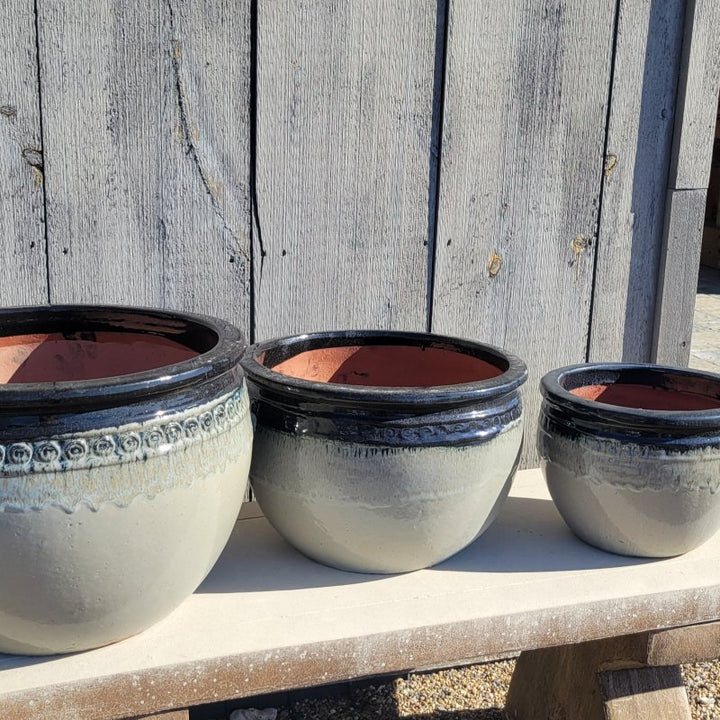 A trio of rounded Ombre Planter with a decorative band of spiral designs under the lip; this trio is heathered gray and black, and depicts sizes Extra Large, Large, and Medium.