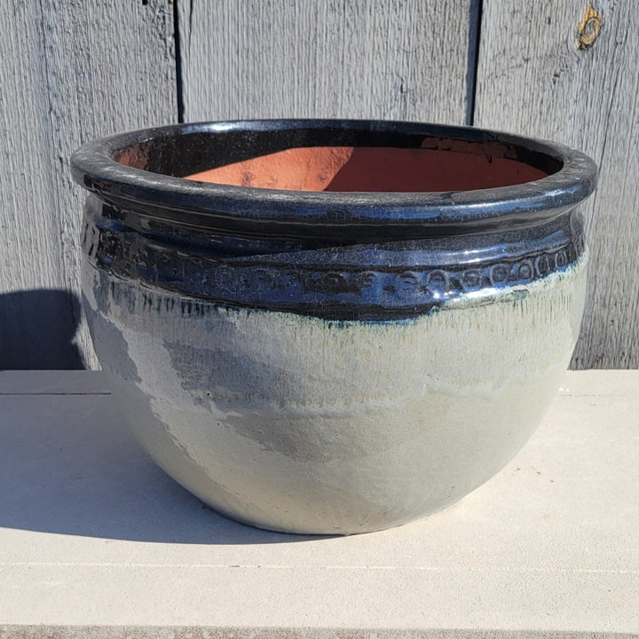 A rounded Ombre Planter with bowed walls, a pronounced lip, and a decorative band of spiral designs under the lip; this finish goes from heathered gray to black.