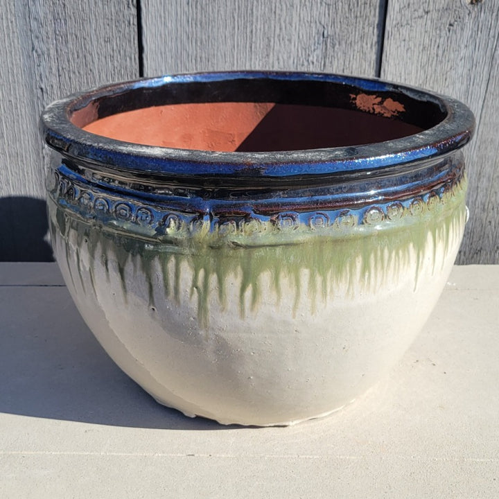 A rounded Ombre Planter with bowed walls, a pronounced lip, and a decorative band of spiral designs under the lip; this finish is cream white, green, and mirror-black.