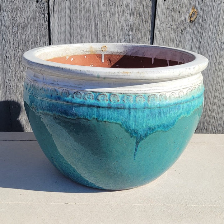 A rounded Ombre Planter with bowed walls, a pronounced lip, and a decorative band of spiral designs under the lip; this finish is teal green, light blue, and white.