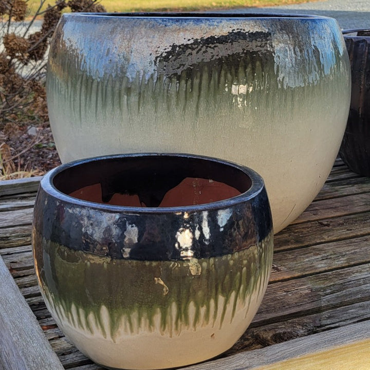 A pair of rounded Oval planters with bowed walls; both are finished with a cream-white to hunter green to reflective mirror black ombre glaze.