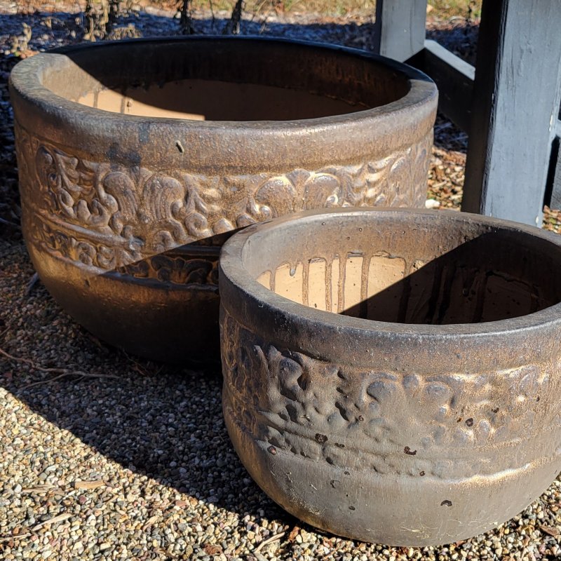 A pair of weathered bronze glazed Quebrada planters with Mesoamerican-inspired designs.