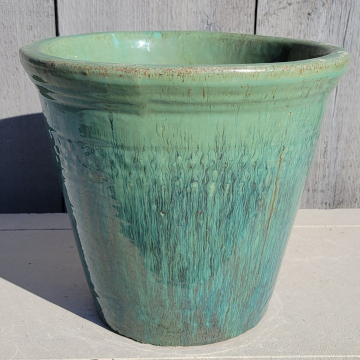 A rounded, flared planter with a faint divot pattern and a pronounced rolled rim; finished with a sea-foam and darker jade green 'Glacier' glaze. 