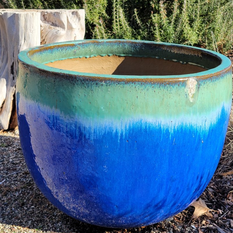 A large, round, planter with plain sides; finished with a dark blue to jade green ombre glaze.