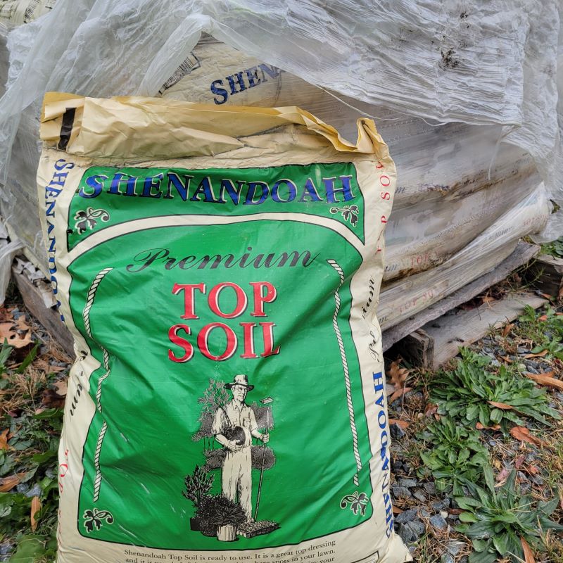 A photo of Shenandoah Premium Top Soil in a green and beige bag with red text