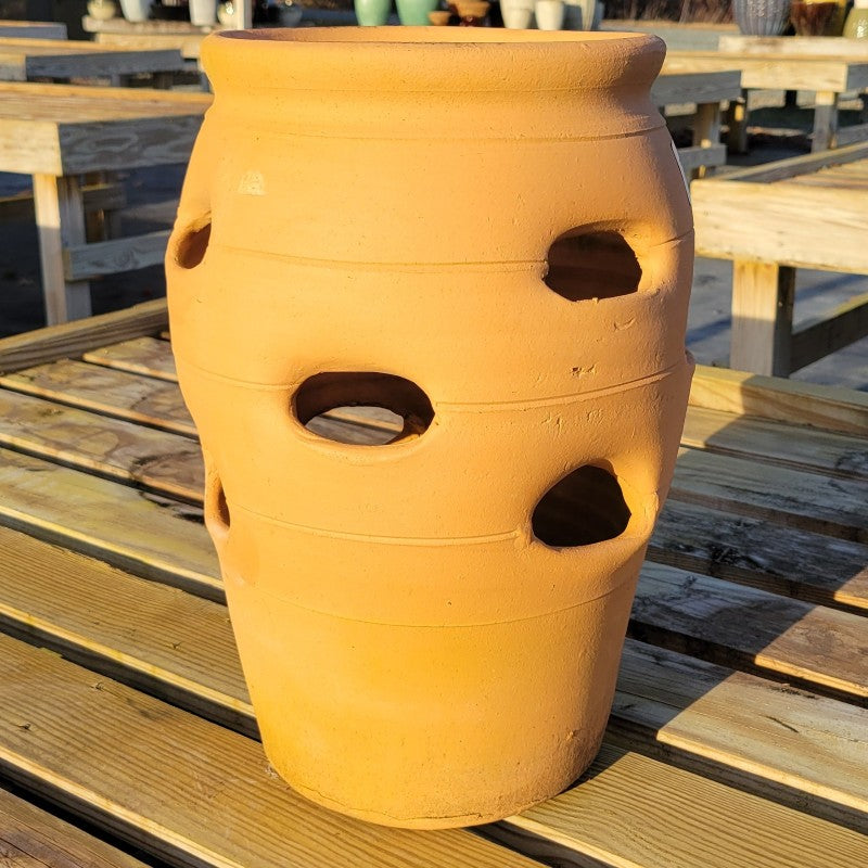 An urn-shaped terracotta pot with 12 open-air nooks for growing strawberries or hanging plants from the sides.