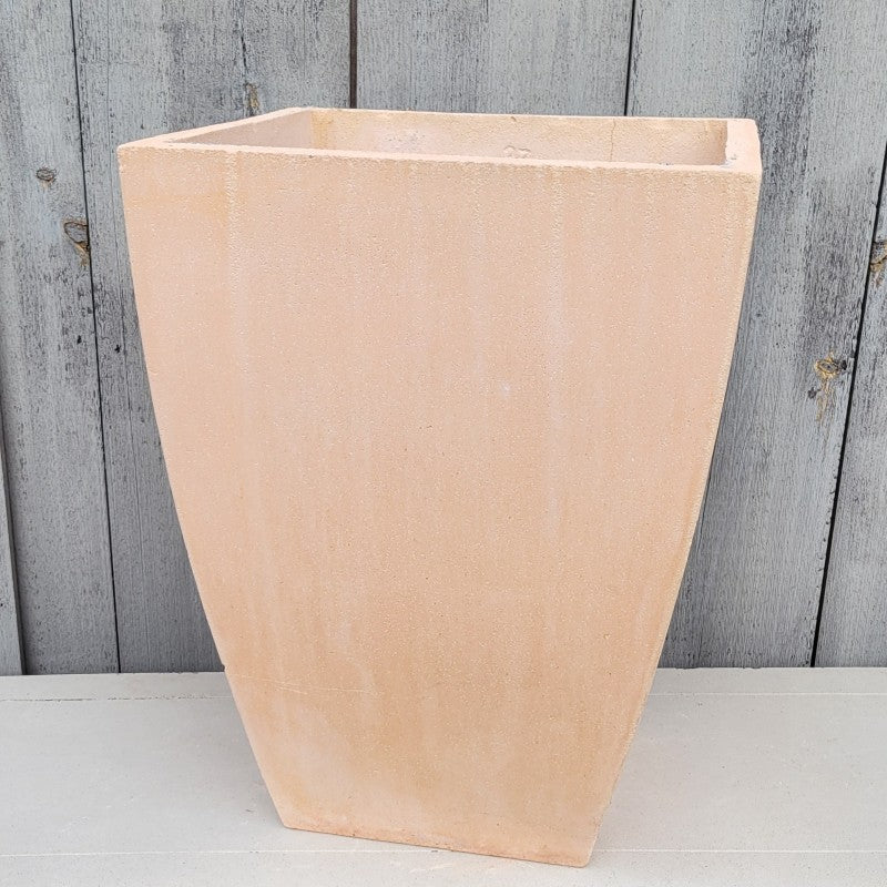 A tall, square, fiberglass Milan planter with bowed walls; finished with a matte sandy-pink glaze meant to resemble faded terra cotta.